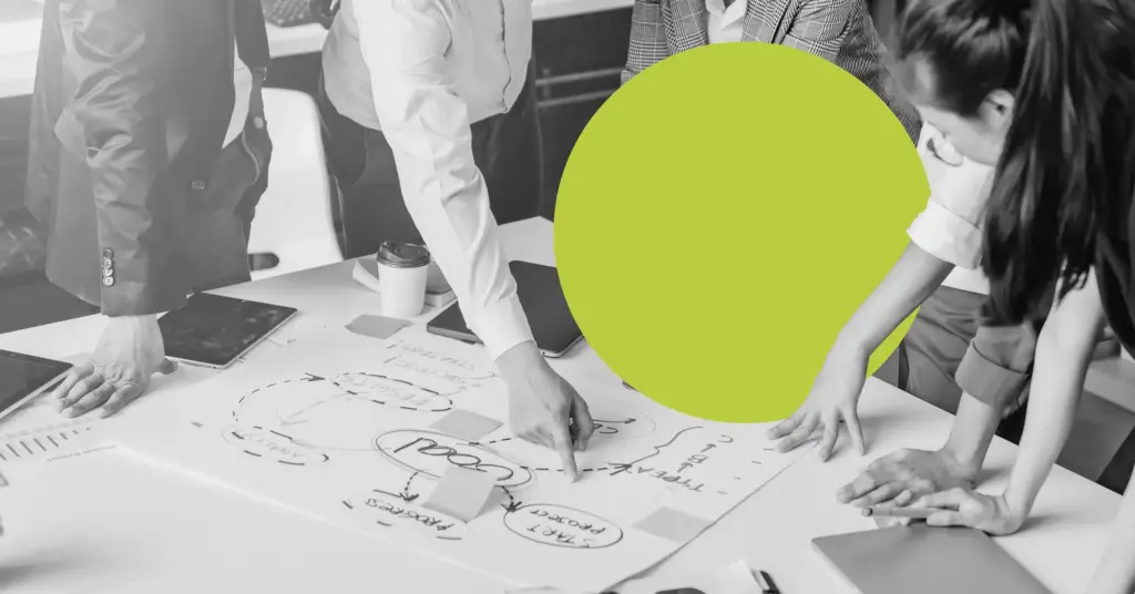 executives pointing to a lead generation strategy for manufacturing laid out on an office table.