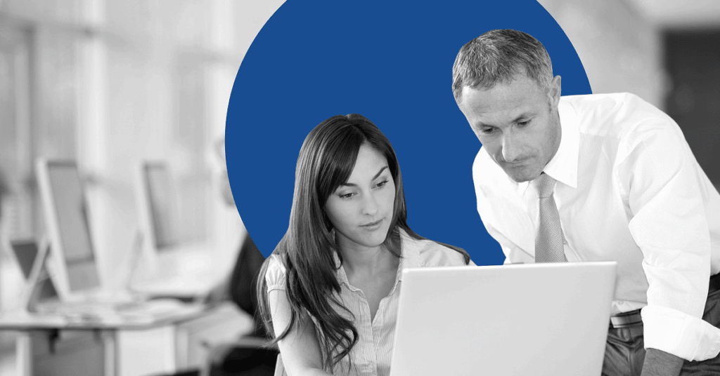 Two business professionals collaborating at a laptop in an office setting.